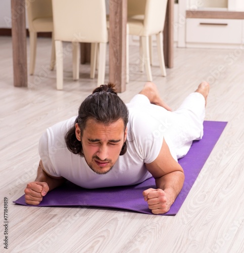 Young man doing physical exercises at home