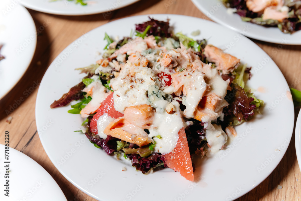 Gourmet Salad with Smoked Salmon and Cheese. Close-up of a gourmet salad with smoked salmon, grated cheese, mixed greens, and grapefruit slices, served on a white plate. Gourmet Salad with Smoked Salmon and Cheese. Close-up of a gourmet salad with smoked salmon, grated cheese, mixed greens, and grapefruit slices, served on a white plate.