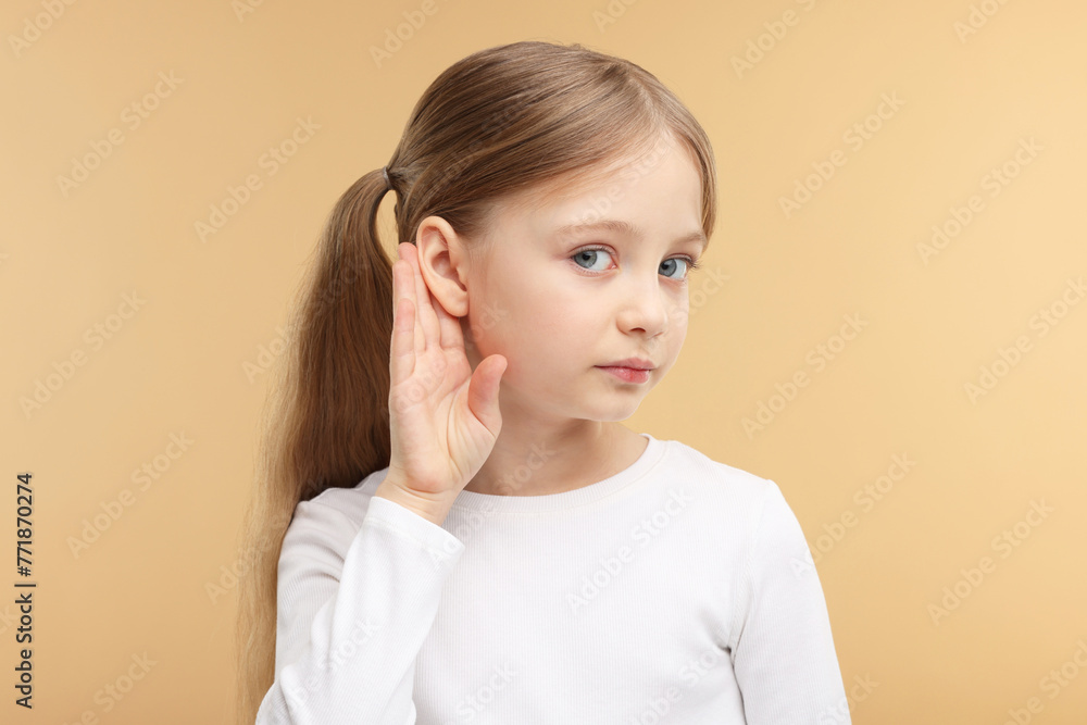 Little girl with hearing problem on pale brown background Little girl with hearing problem on pale brown background
