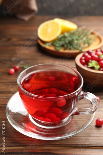 Tasty hot cranberry tea in glass cup and fresh berries on wooden table