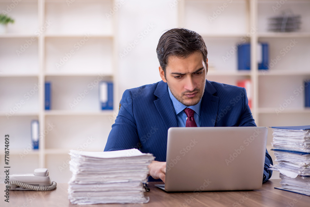 Young male employee and too much work in the office Young male employee and too much work in the office
