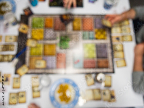 defocused board game from above with people playing photo