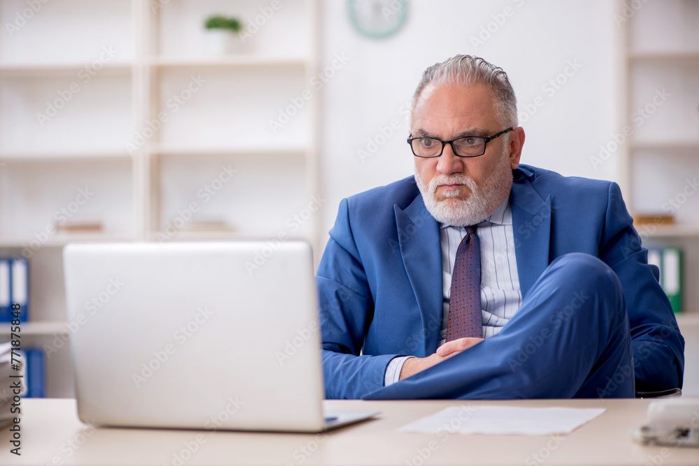 Old male employee working in the office Old male employee working in the office