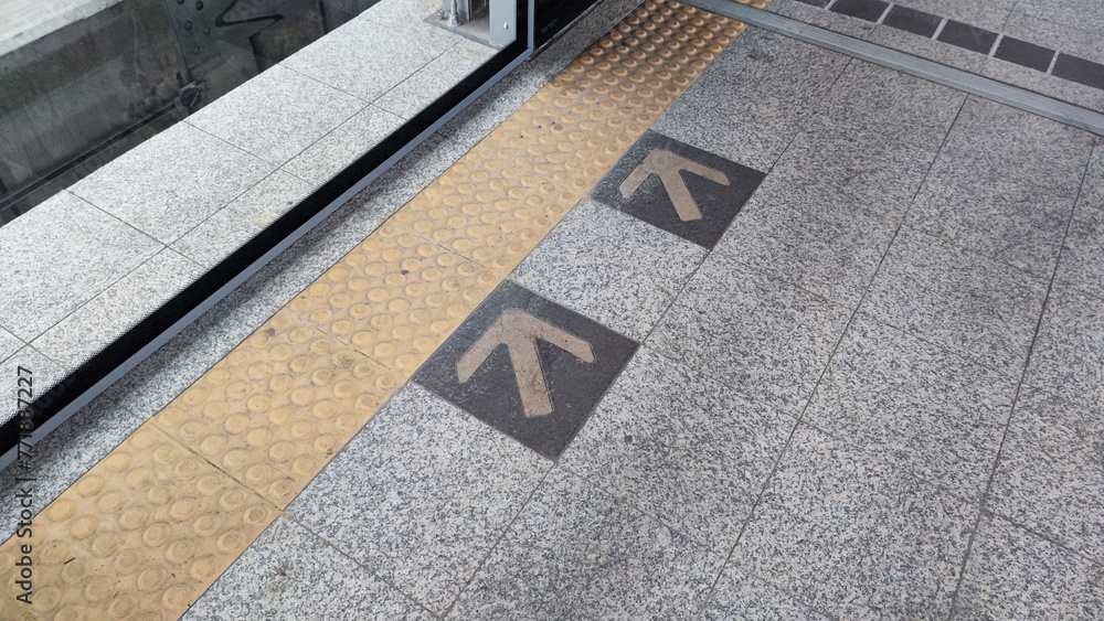 Fototapeta premium Directional markers on the platform guide passengers awaiting the sky train, with yellow arrows delineating the path