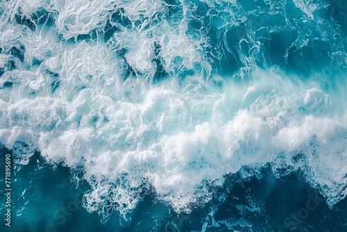 An Abstract aerial texture of white ocean wave foam over turquoise waters.