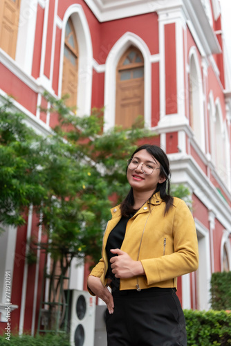 Beautiful asian woman (LGBTQ) natural makeup wear fashion yellow leather clothes with glasses posing at old town and vintage building outdoor fashion style photo