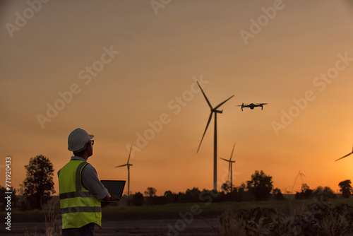 silhouette of a person with a wind turbine. Silhouette Service engineers checking wind turbine on tablet on wind turbine farm Power Generator on background Station on mountain, Thailand people