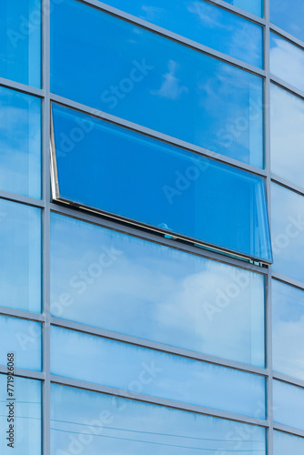 Blue glass reflects cloudy sky modern building facade exterior office texture background abstract