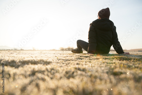 公園の芝生で朝焼けを眺める男性

