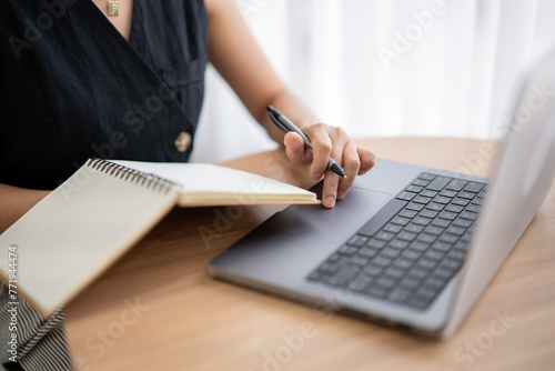 Close-up of Woman Working on Laptop with Notebook