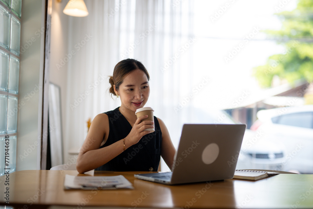 Smiling Woman Enjoying Coffee While Working on Laptop Smiling Woman Enjoying Coffee While Working on Laptop