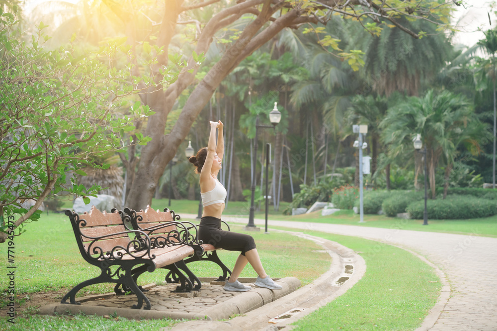 Woman jogger refreshing and sitting over bench in a park after running Woman jogger refreshing and sitting over bench in a park after running