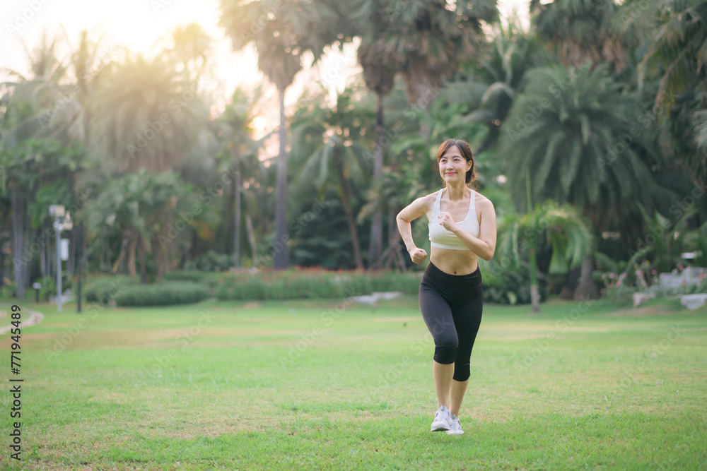 pretty asian woman jogger running in green nature public park.