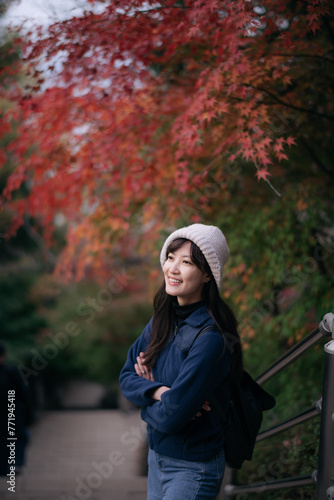 Asian woman in Japan's fall beauty, a cheerful holiday portrait in Kyoto. Vibrant foliage, friends, and smiles by the lake create a joyful and scenic atmosphere.