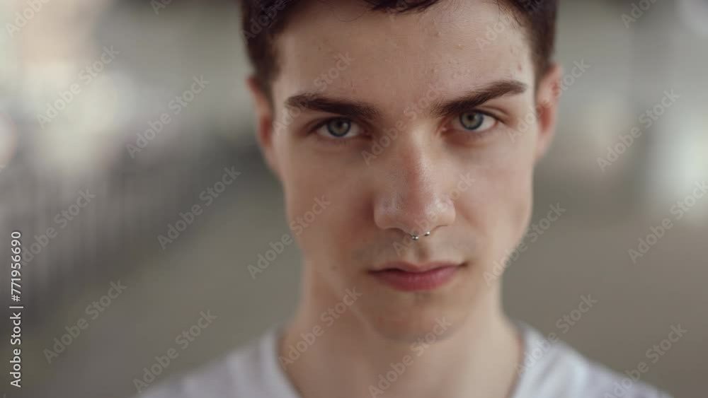 Slow motion. Close-up. Face of an upset guy looking at the camera while standing outdoors in the city during the day Slow motion. Close-up. Face of an upset guy looking at the camera while standing outdoors in the city during the day