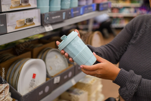 Woman's hand holding a ceramic vase in a supermarket. Concept of shopping.