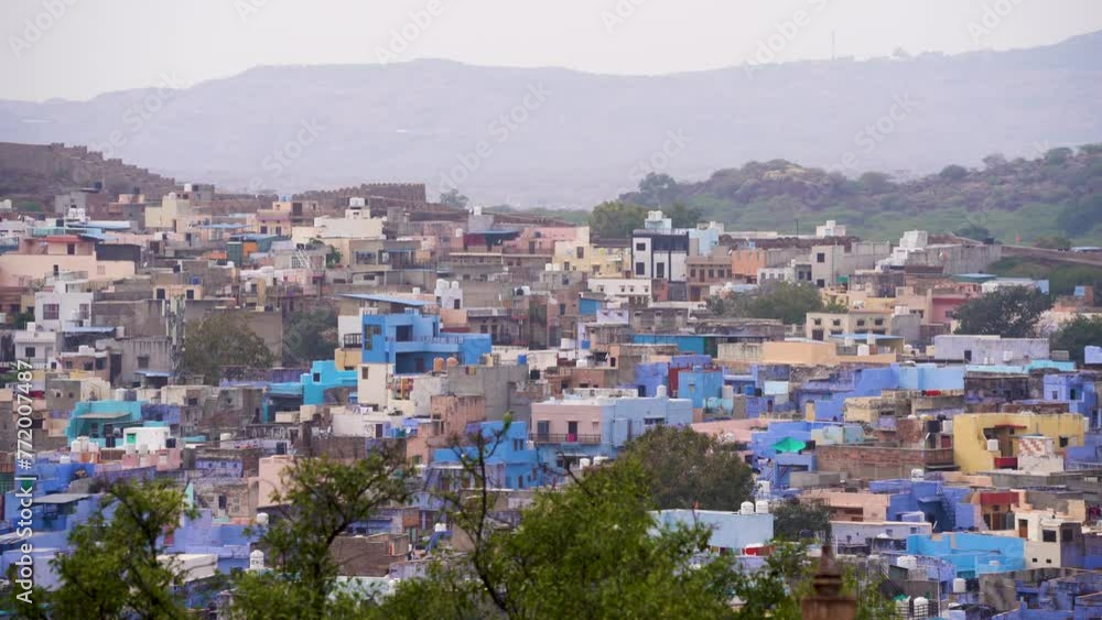 Aerial drone panning shot showing densely packed homes residences in blue city of Jodhpur Rajasthan with aravalli hills in the background a popular tourist destination Aerial drone panning shot showing densely packed homes residences in blue city of Jodhpur Rajasthan with aravalli hills in the background a popular tourist destination