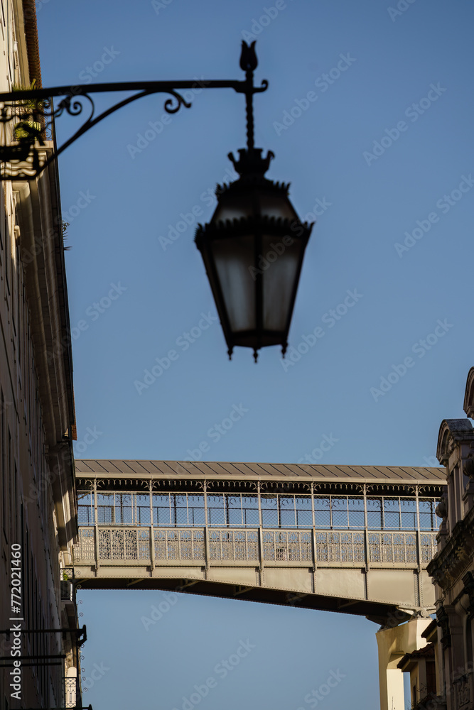 Walkway of the Santa Justa Lift in Lisbon, Portugal and out of focus antique street light in the foreground Walkway of the Santa Justa Lift in Lisbon, Portugal and out of focus antique street light in the foreground