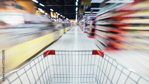 Time lapse of shopping trolley rushing inside supermarket full of food products and people. Retail store and consumerism concept.