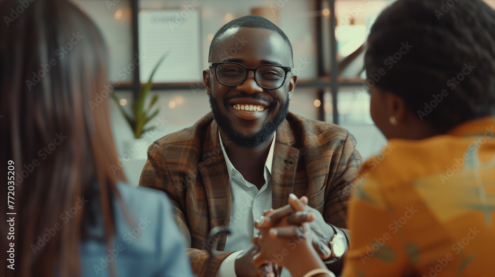 Happy black financial advisor handshaking with his clients during meeting in office