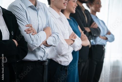 Diverse group of professional business people stand in line with cross arm gesture in modern corporate office. Happy and smiling multiracial office worker team bond and succeed together. Concord