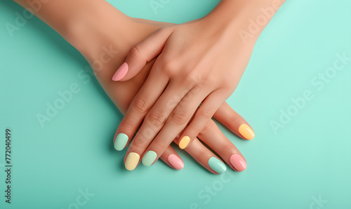 Female hands with pastel multicolored manicure elegantly crossed over a turquoise background, Generative AI