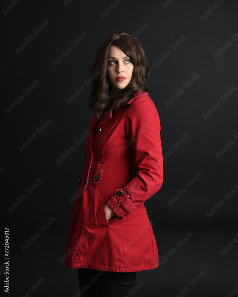 close up portrait of beautiful brunette woman model, wearing red trench coat.isolated on dark studio background with shadows. hands in jacket pockets. close up portrait of beautiful brunette woman model, wearing red trench coat.isolated on dark studio background with shadows. hands in jacket pockets.