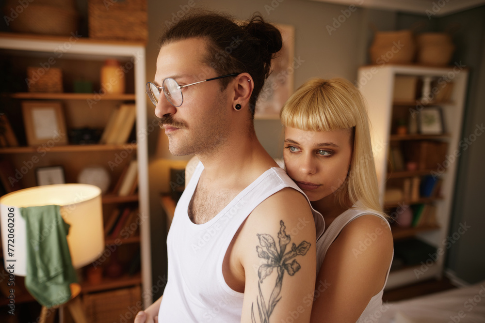 Beautiful woman embracing tattooed boyfriend in bedroom