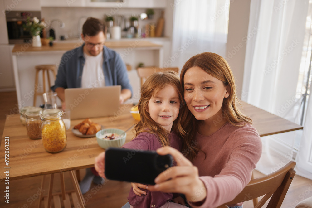 Mother and daughter taking Selfie with smart phone during breakfast at home Mother and daughter taking Selfie with smart phone during breakfast at home