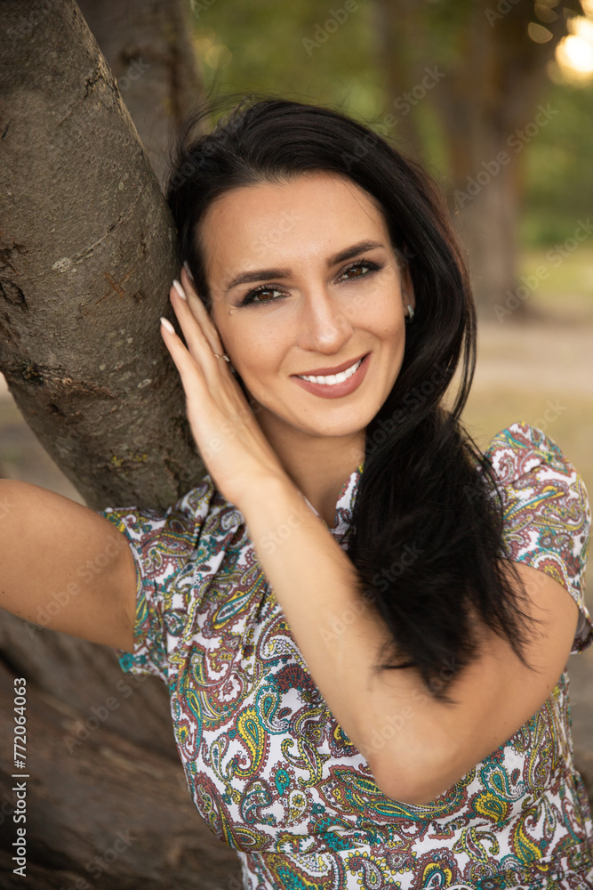 Portrait of a beautiful dark-haired young woman, girl on a background of summer sunset and a green park. Portrait of a beautiful dark-haired young woman, girl on a background of summer sunset and a green park.