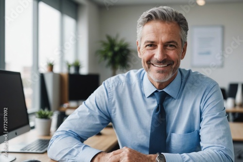 Happy mature businessman leaning on desk in office