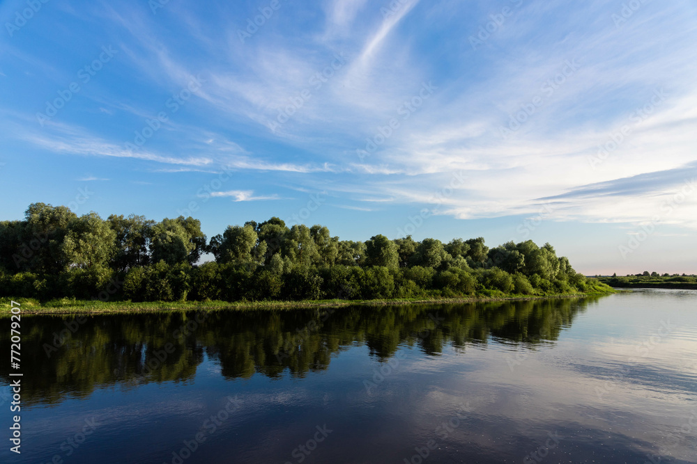 European landscape, river, blue sky on a background of green trees.