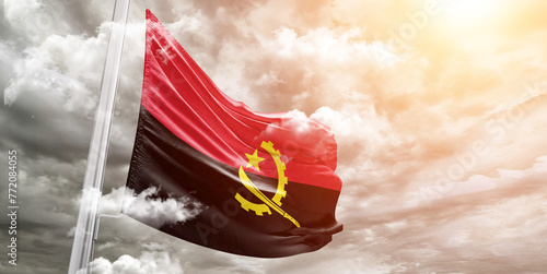 Fotografie Angola national flag cloth fabric waving on beautiful cloudy Background