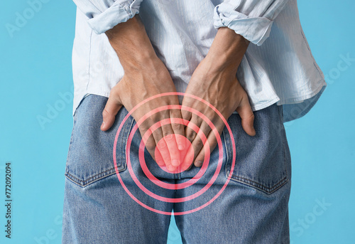 Fotografia Young man with hemorrhoids on blue background, back view