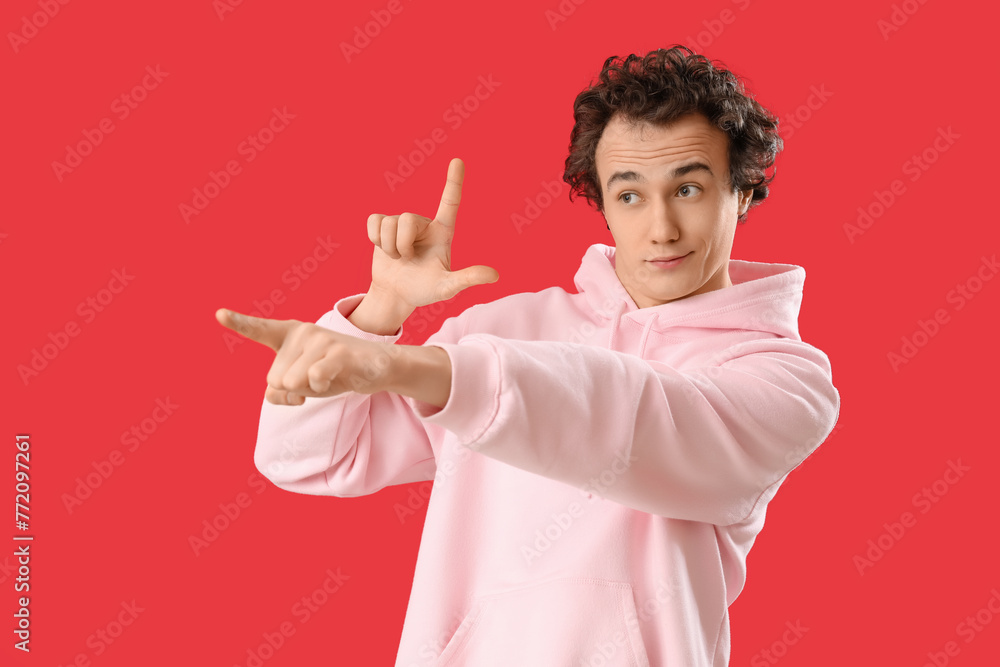 Fotografie Young man showing loser gesture on red background