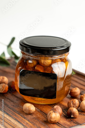 jar of honey with nuts on a white background and a leaf