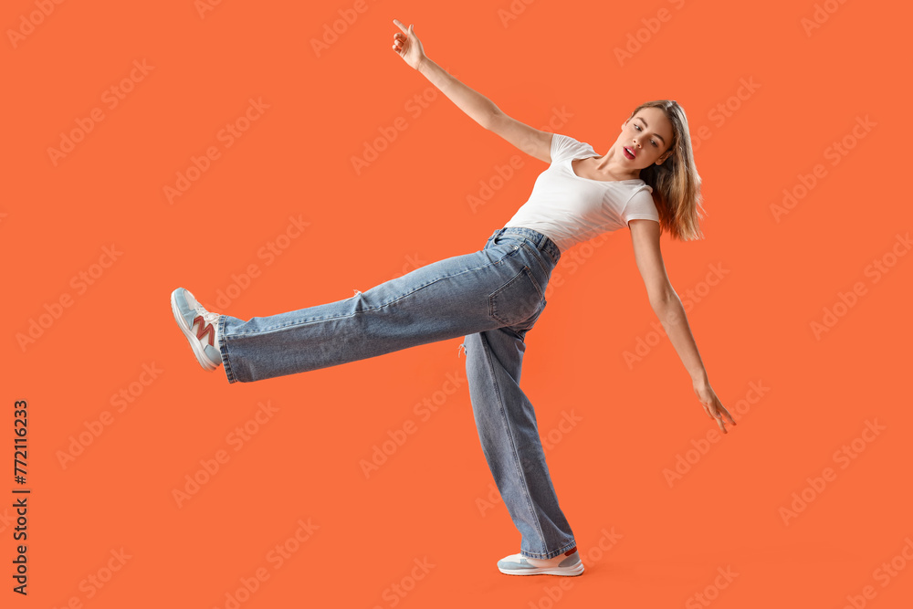 Young woman in stylish jeans on orange background - obrazy, fototapety, plakaty 