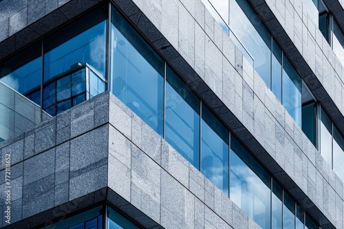 A granite facade of a sleek and contemporary tall building with many windows