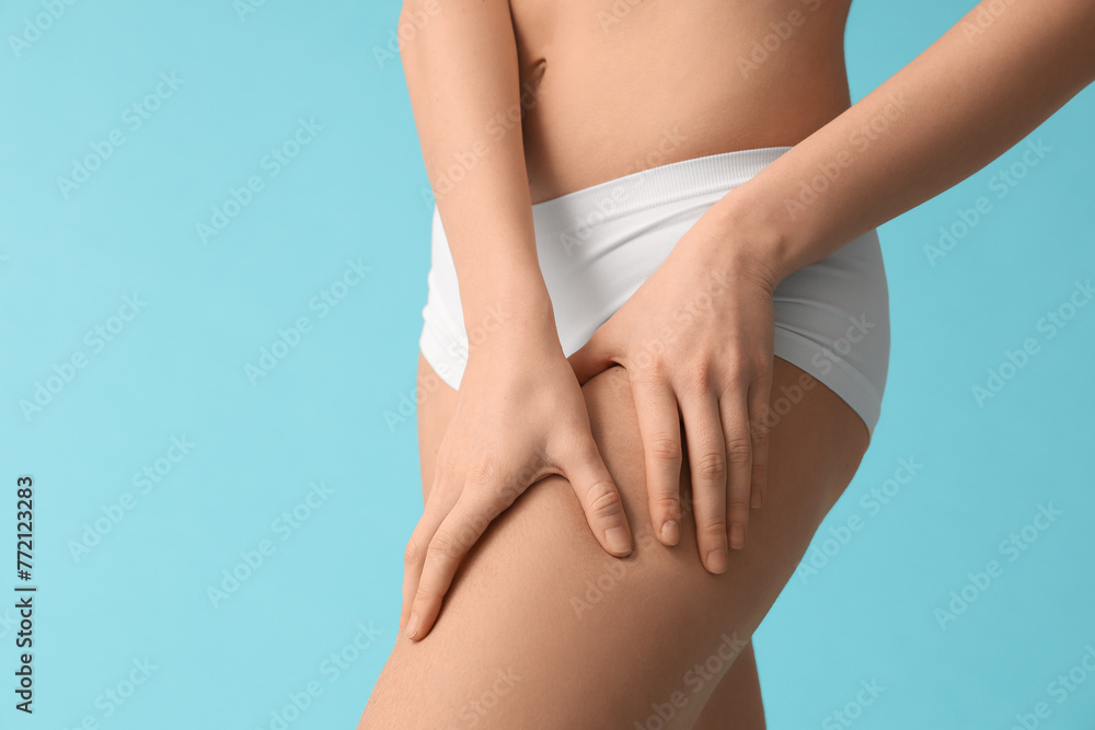 Beautiful young woman with cellulite problem on blue background