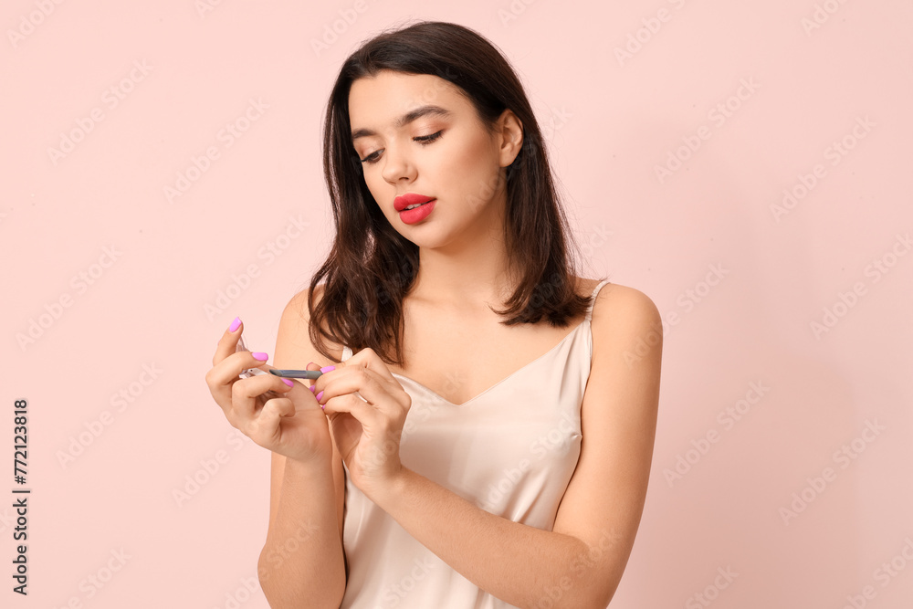 Beautiful young woman with eyeshadows and brush on pink background