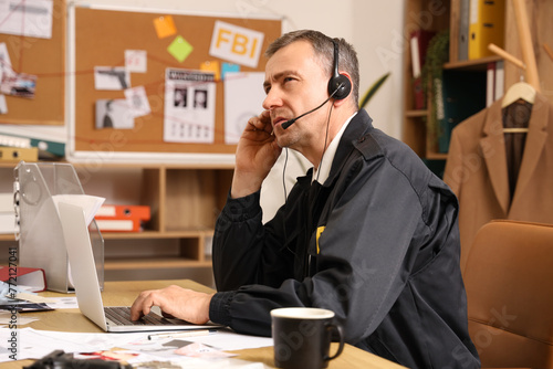 Mature FBI agent with headset working at table in office