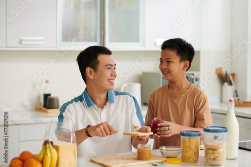 Happy Vietnamese father and son making sandwiches for breakfast