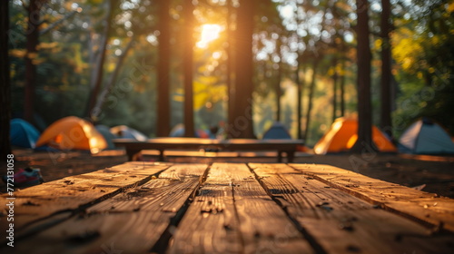 a wooden table in front of a group of tents camping with sunset background