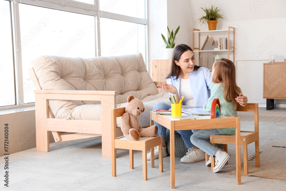 Female psychologist with little girl reading book at table in office Female psychologist with little girl reading book at table in office