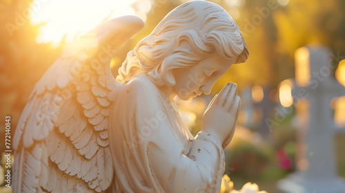 Angel statue praying on graveyard close up photo. Blurred cemetery background. In loving memory