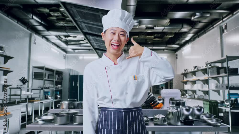 Asian Woman Chef Smiling And Making Call Me Gesture To Camera In Professional Kitchen Asian Woman Chef Smiling And Making Call Me Gesture To Camera In Professional Kitchen