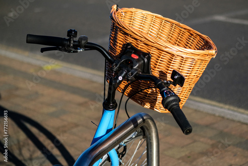 Staitionenry Blue Bicycle With A Wicker Shopping Basket Attached To Handlebars