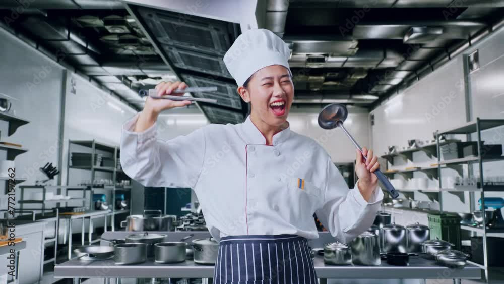 Asian Woman Chef Holding Tongs And Ladle And Dancing In Professional Kitchen Asian Woman Chef Holding Tongs And Ladle And Dancing In Professional Kitchen
