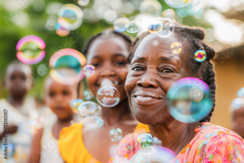 A joyful elderly woman and young children playing with bubbles outdoors on a sunny day, reflecting family happiness and fun.