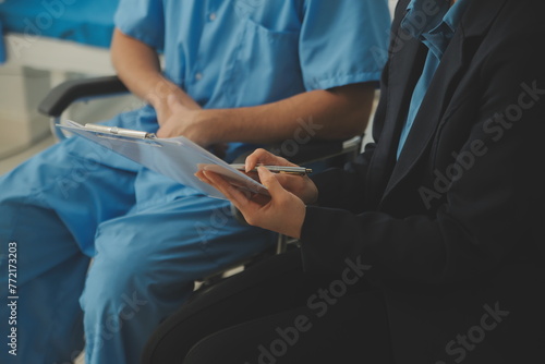 Midsection of female nurse checking blood pressure of woman sitting on wheelchair in clinic